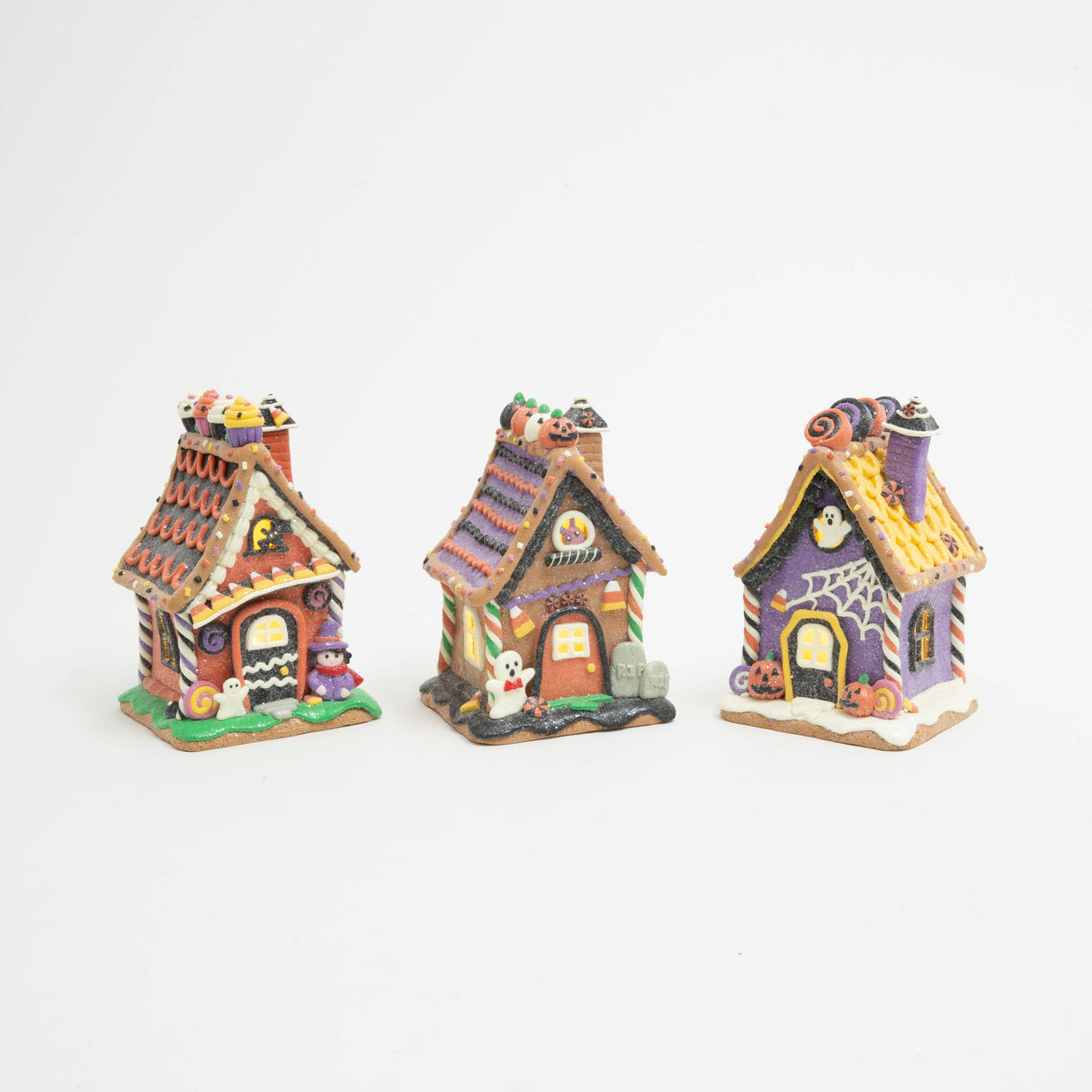 Witch’s Candy Corn Cottage: Lighted Halloween gingerbread house with candy corn awning, cupcakes on the roofline, a purple‑clad witch, a small ghost, and a bat in the attic window.
Ghostly Coffin Cottage: Lighted Halloween gingerbread house with a coffin‑shaped door, ghost in the attic window, spiderweb front detail, jack‑o‑lanterns, and purple‑yellow roof.
Ghost & Gravestone Gingerbread House: Lighted Halloween gingerbread house with a ghost out front, tombstones beside the door, jack‑o‑lantern roofline,