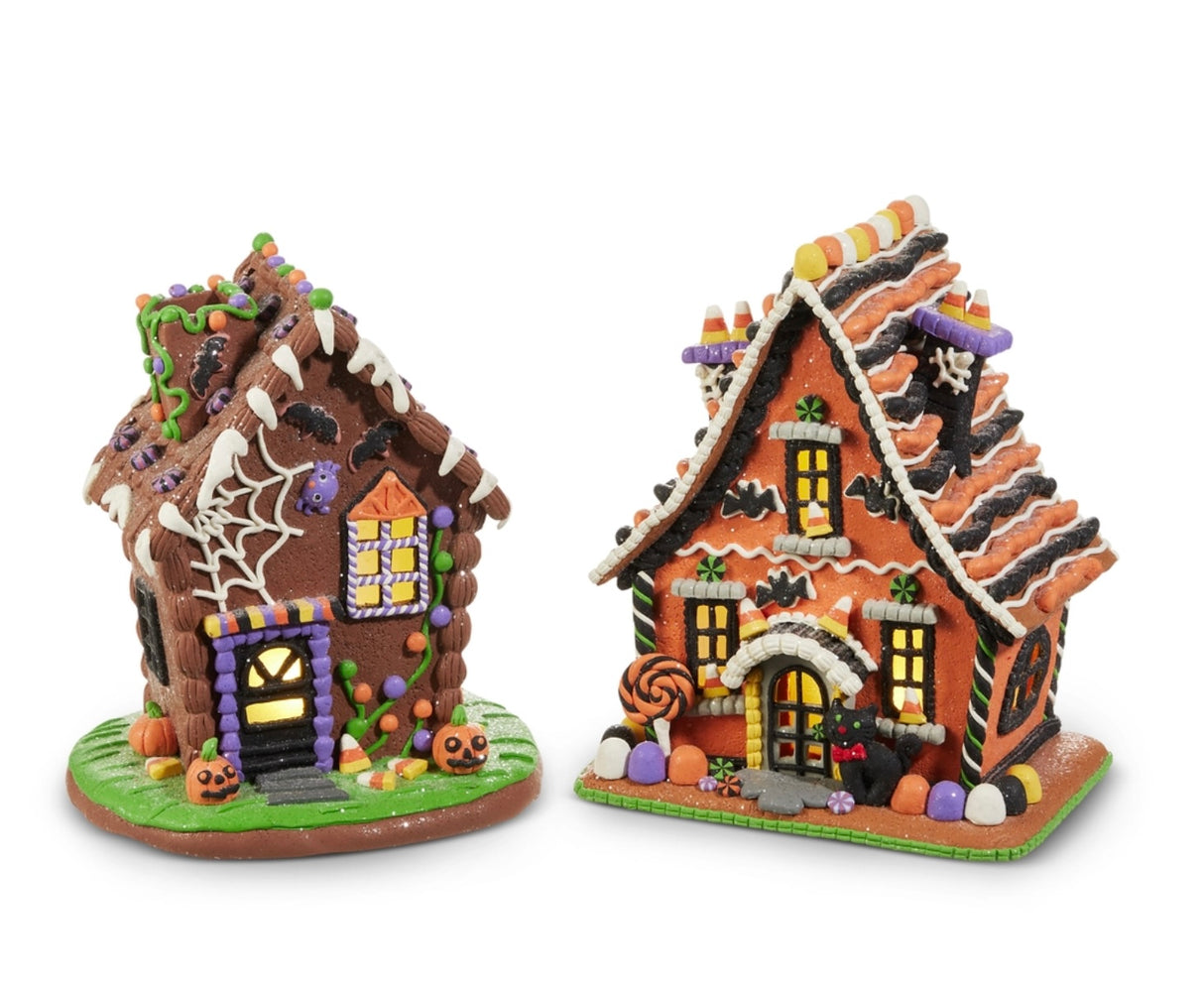 Two assorted Halloween gingerbread houses made of clay dough: Spiderweb Cottage with chocolate façade and icing webs, and Candy Corn Manor with orange walls and candy trim