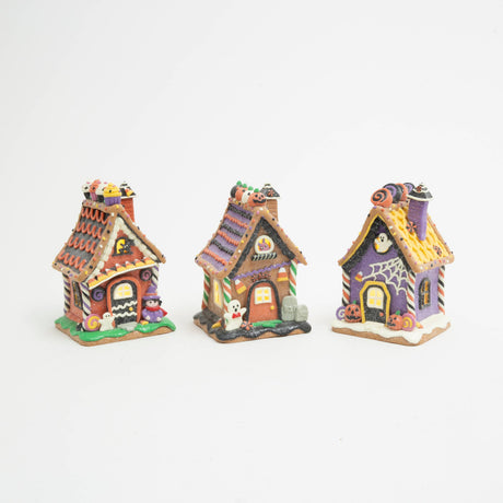 Witch’s Candy Corn Cottage: Lighted Halloween gingerbread house with candy corn awning, cupcakes on the roofline, a purple‑clad witch, a small ghost, and a bat in the attic window.

Ghostly Coffin Cottage: Lighted Halloween gingerbread house with a coffin‑shaped door, ghost in the attic window, spiderweb front detail, jack‑o‑lanterns, and purple‑yellow roof.

Ghost & Gravestone Gingerbread House: Lighted Halloween gingerbread house with a ghost out front, tombstones beside the door, jack‑o‑lantern roofline,