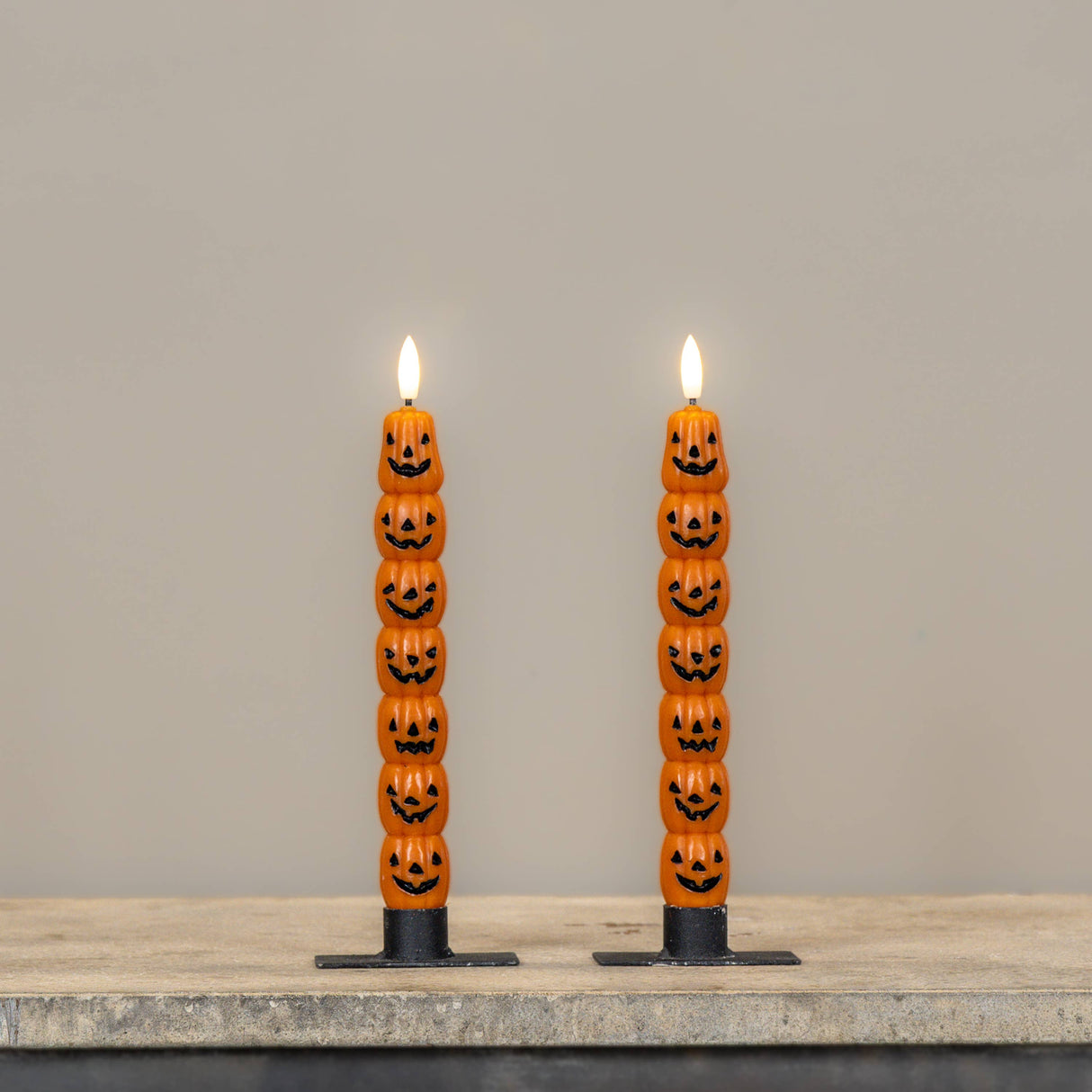 Set of two 9.75" stacked jack‑o’-lantern LED taper candles with realistic 3D moving flame, styled in black holders.