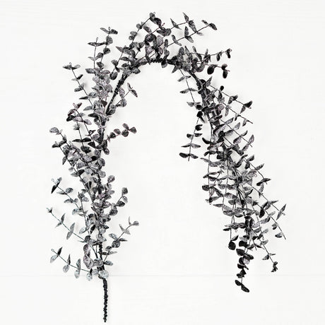 A slim black eucalyptus garland with delicate leaves and subtle glitter displayed against a white background.
