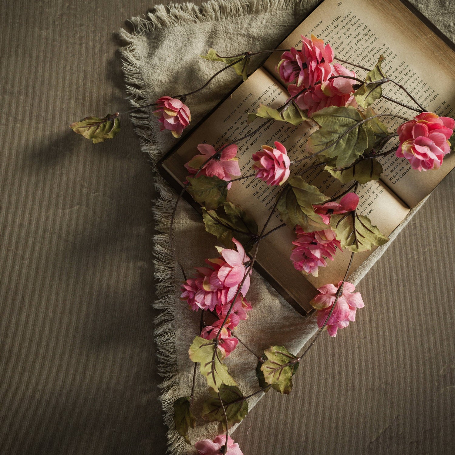 Dark pink 39-inch faux hops stem draped across an open book with green leaves.