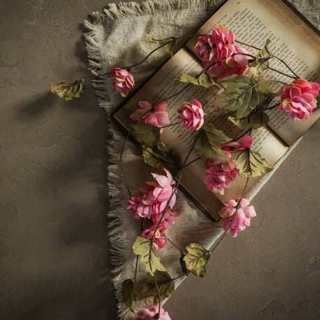 Dark pink 39-inch faux hops stem draped across an open book with green leaves.