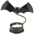 Metal bat candle holder with a flying bat silhouette illuminated by a tealight on a dark surface.