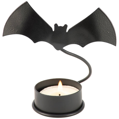 Metal bat candle holder with a flying bat silhouette illuminated by a tealight on a dark surface.
