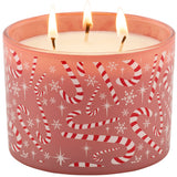 A three-wick holiday candle in a frosted pink glass container with red and white candy cane and snowflake patterns, shown lit on a white background.
