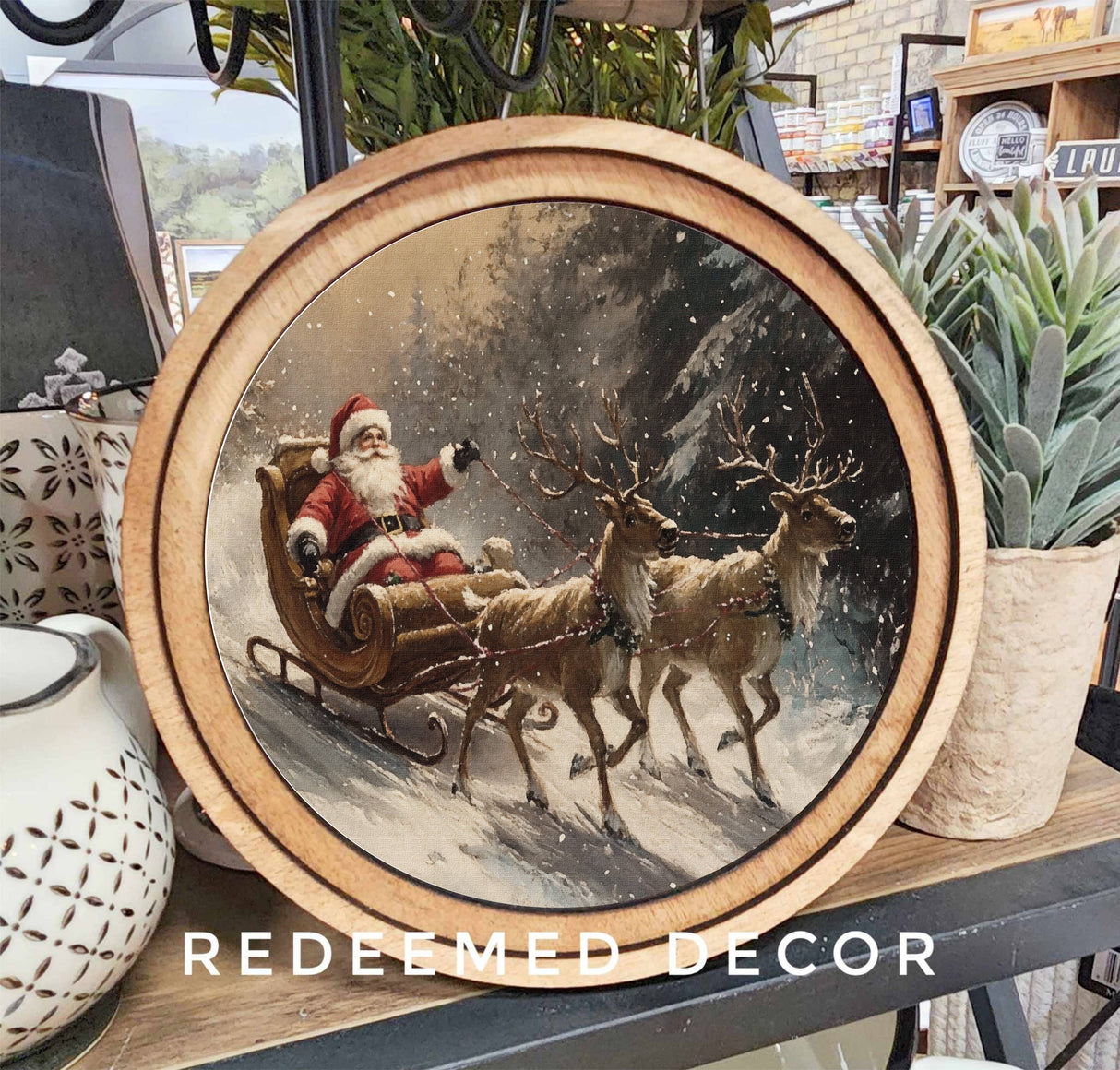 Decorative canvas art with Santa Claus in a sleigh and reindeer in a snowy scene.