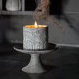 Decorative candle with bat design on a stand against a dark background