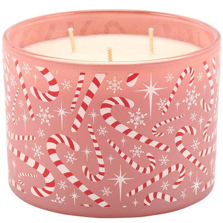 A pink frosted glass jar candle with three wicks, decorated with a festive pattern of red and white striped candy canes, white snowflakes, and white starbursts.