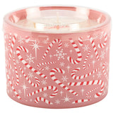 A pink holiday-themed candle in a clear plastic tub with a red and white candy cane and snowflake pattern, shown on a white background.