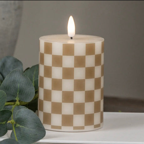4" Pillar: Gold checked LED pillar candle styled with white books, eucalyptus, and a ceramic vase.