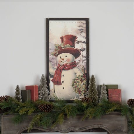 Hand‑painted metal snowman wall hanging with red hat and scarf in a snowy evergreen scene.