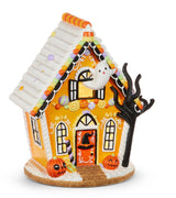 12-inch Halloween gingerbread house with orange walls, ghost in attic, pumpkins, witch hat door, black tree, and cookie base; light-up with timer