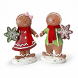 Two glittered gingerbread children figurines stand on frosted snow bases, each holding a snowflake-shaped cookie with white icing details. One figure features a red snowflake cookie and coordinating red outfit accents, while the other holds a green snowflake cookie with matching green accents. Both wear bright red scarves and showcase sweet gingerbread-inspired details perfect for Christmas decorating.