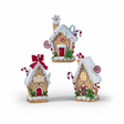Three illuminated gingerbread-style houses feature snowy white icing details, candy cane accents, and warm glowing windows. The collection includes a Snowflake House with a snowflake chimney topper, a Peppermint House with peppermint candy accents, and a Bow House adorned with a large red bow. Each resin cottage is illuminated from within for a cozy holiday glow.
