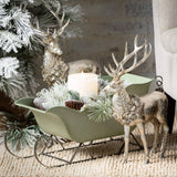 Decorative scene with reindeer, a sleigh, and a candle on a textured surface.