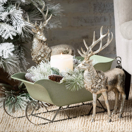 Decorative scene with reindeer, a sleigh, and a candle on a textured surface.