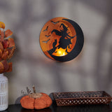 Metal wall candle holder featuring a witch flying across the moon with bat accents, illuminated by a tealight for warm Halloween ambiance.