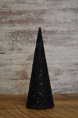 Black glass‑beaded cone tree displayed on a wooden surface with a rustic backdrop, showcasing its sleek shape and shimmering texture.