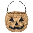 Round woven jack‑o‑lantern basket made of water hyacinth with black faux‑leather handle and cutout pumpkin face.
