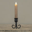 Black metal Serafina taper candle holder with decorative curved legs, shown styled with a taper candle (not included).