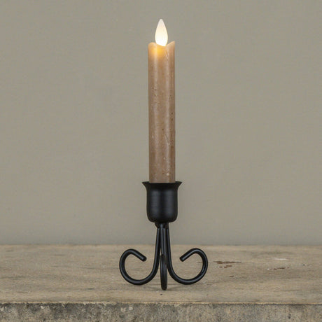Black metal Serafina taper candle holder with decorative curved legs, shown styled with a taper candle (not included).